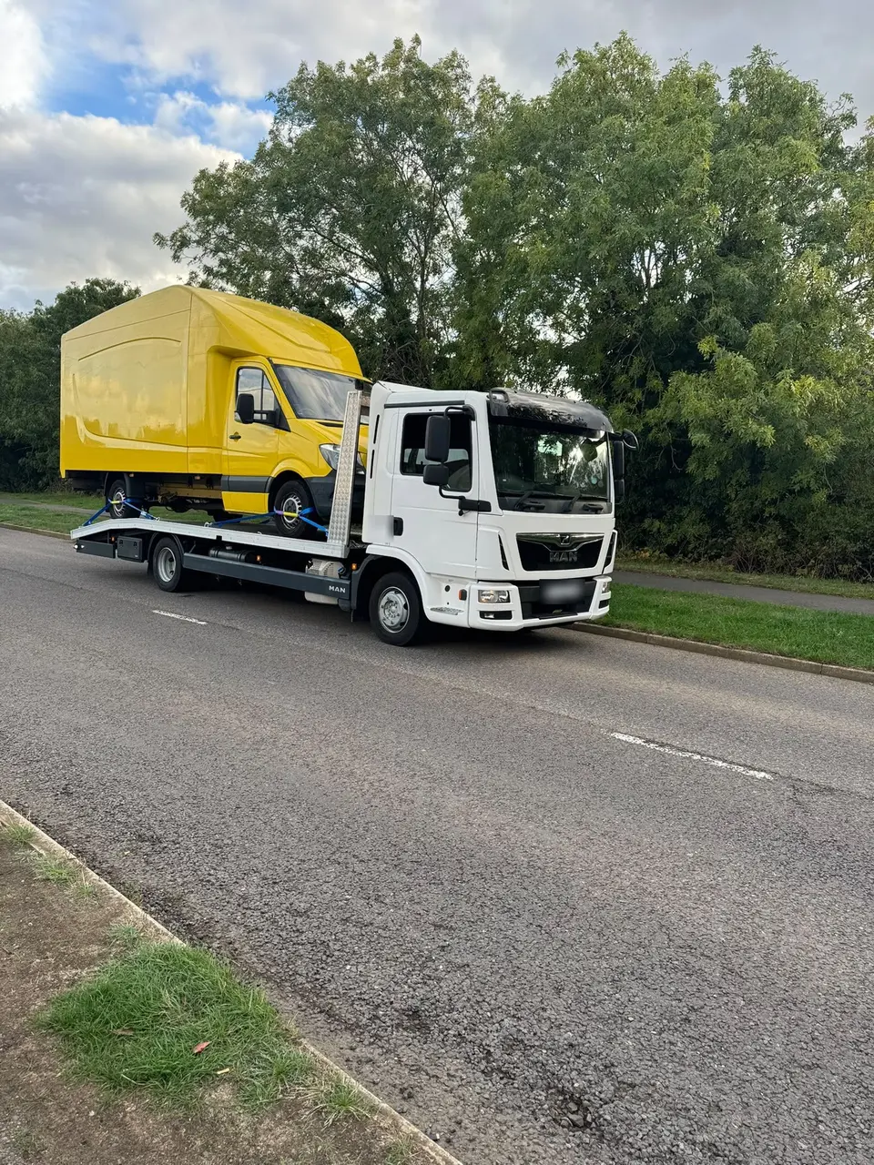 Yellow Luton box van being transported on a white recovery truck