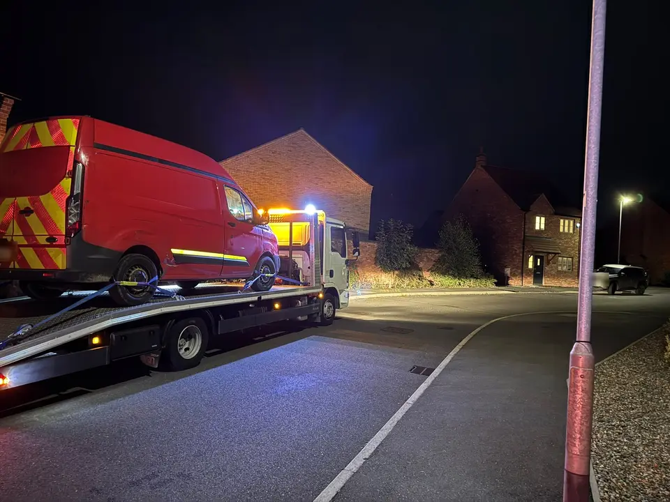 Red van with chevron markings on a recovery truck at night